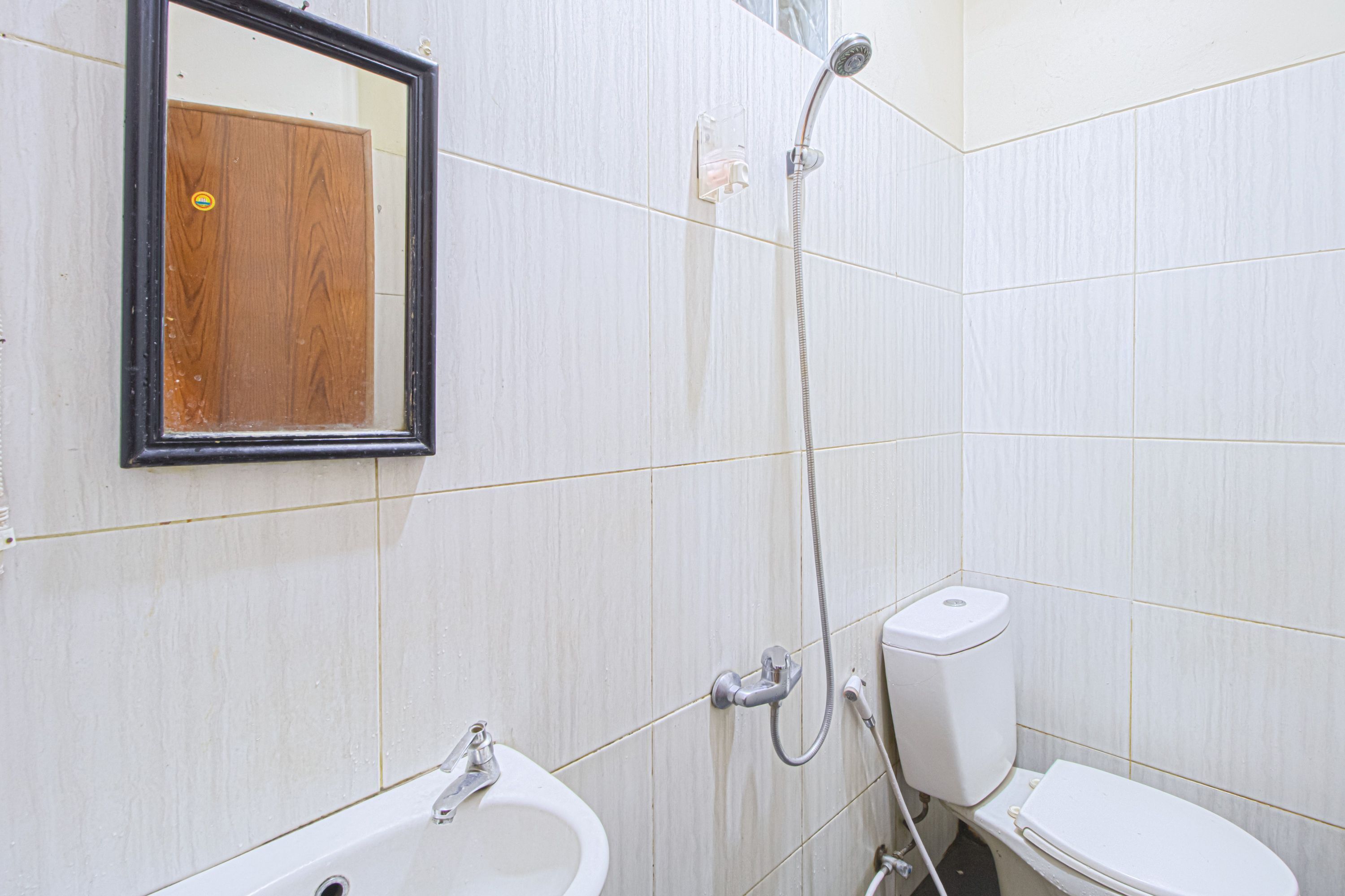 A bathroom with a white sink, mirror, and toilet.