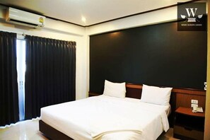 A hotel room with a large bed, a dark headboard, a nightstand with a phone, and an air conditioning unit.