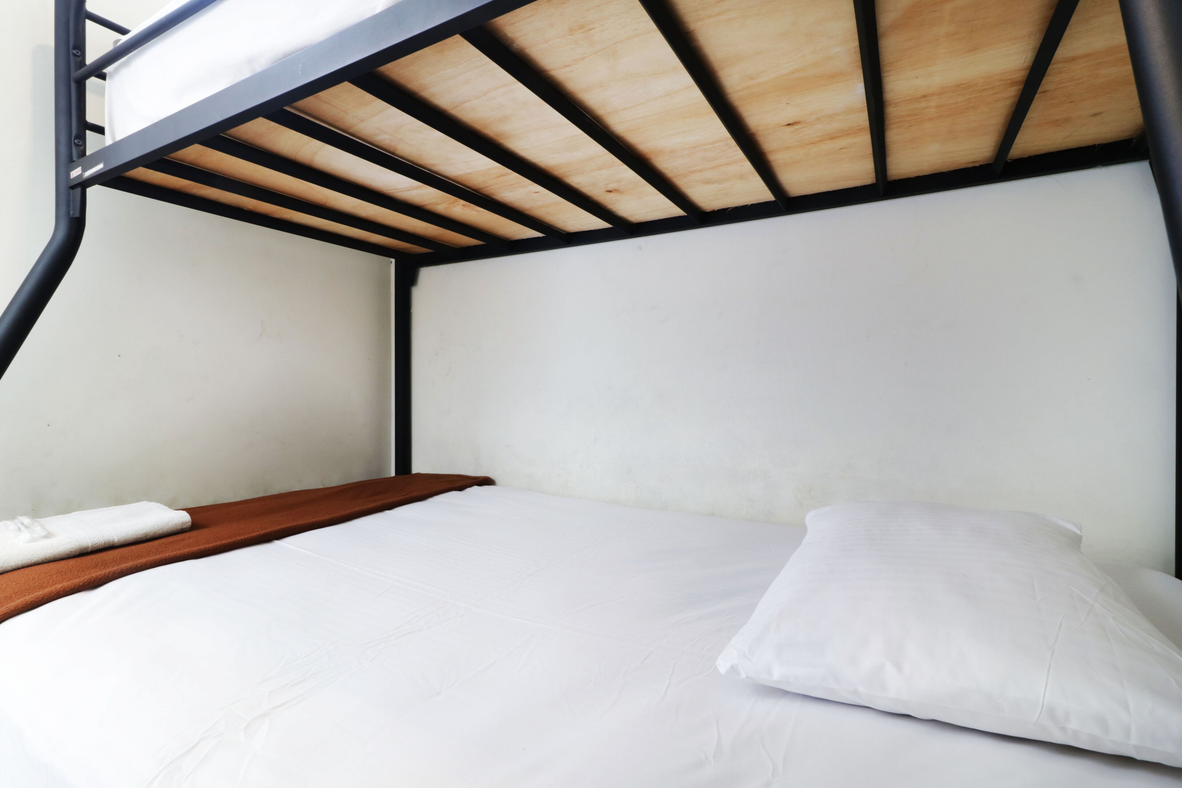 Un lit superposé avec une tête de lit en bois et un matelas blanc.