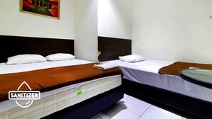 A hotel room with two beds, white bedding, a brown headboard, a painting on the wall, and a visible sanitizer dispenser. - Bantal Guling Pasar Baru Bandung (Bandung)