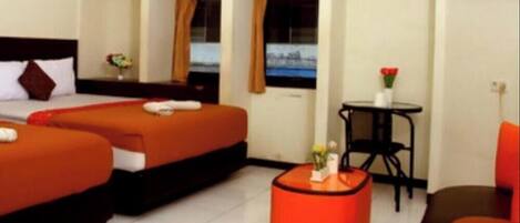 A hotel room with two beds, a small table with a vase, and a chair.