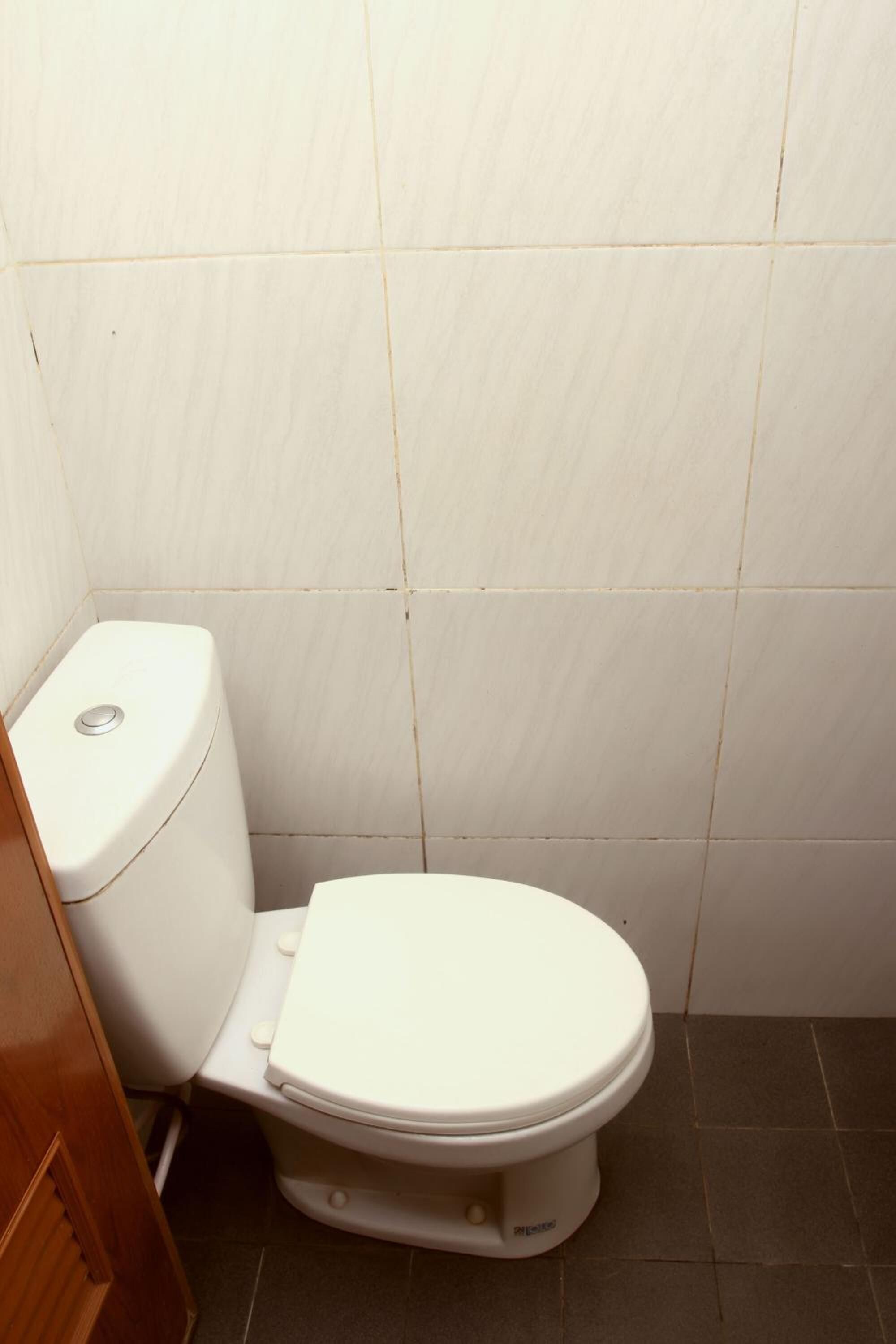 A standard white toilet in a bathroom with tiled walls and floor.
