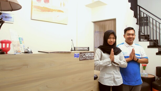 A reception desk with a clock, a red trash bin, and a framed picture on the wall. - Bantal Guling Pasar Baru Bandung (Bandung)