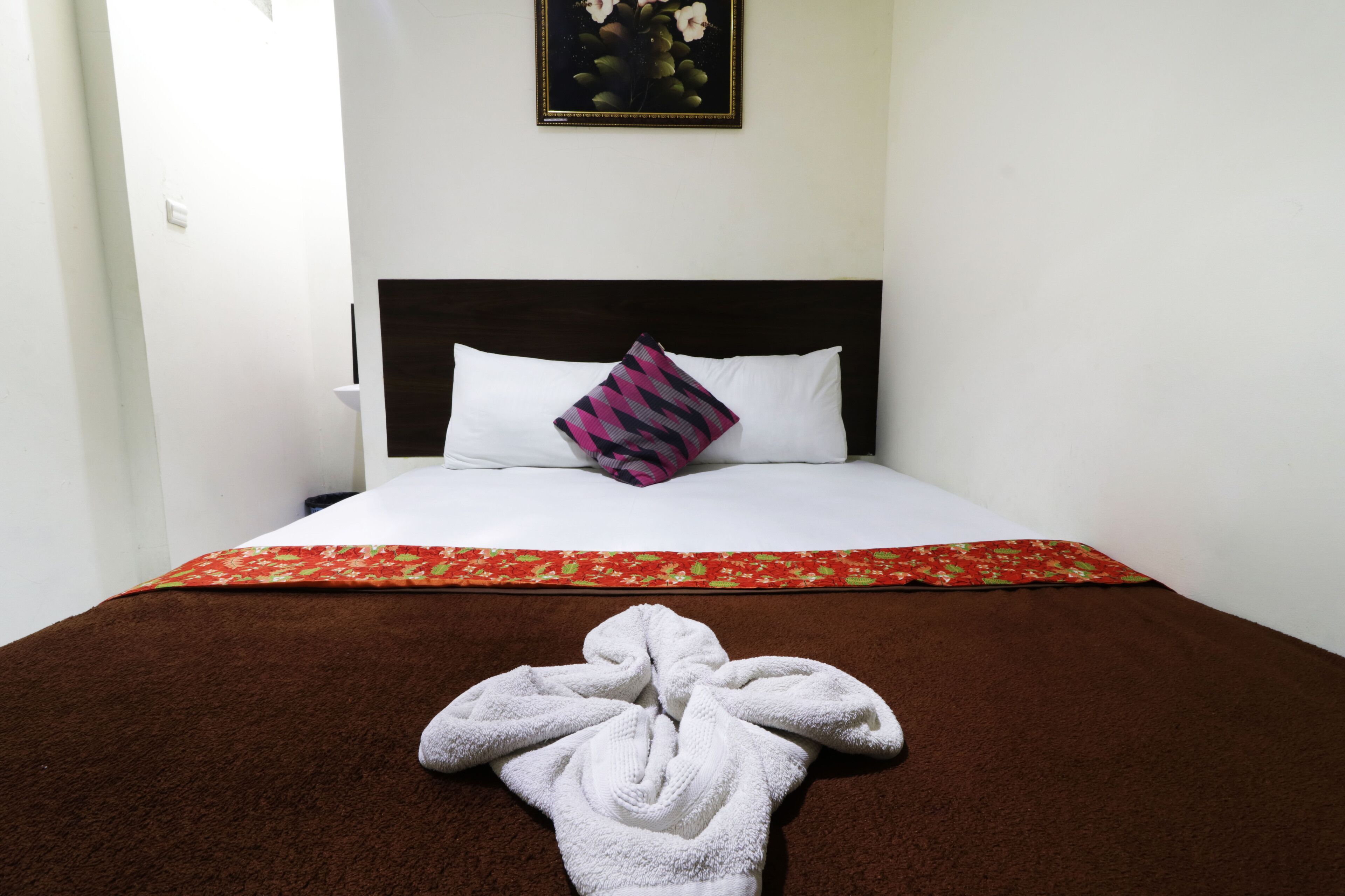 Una habitación de hotel con una cama, almohada, manta y toalla.