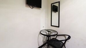 A small room with a single bed, a bedside table, and a wall-mounted TV. - Bantal Guling Pasar Baru Bandung (Bandung)