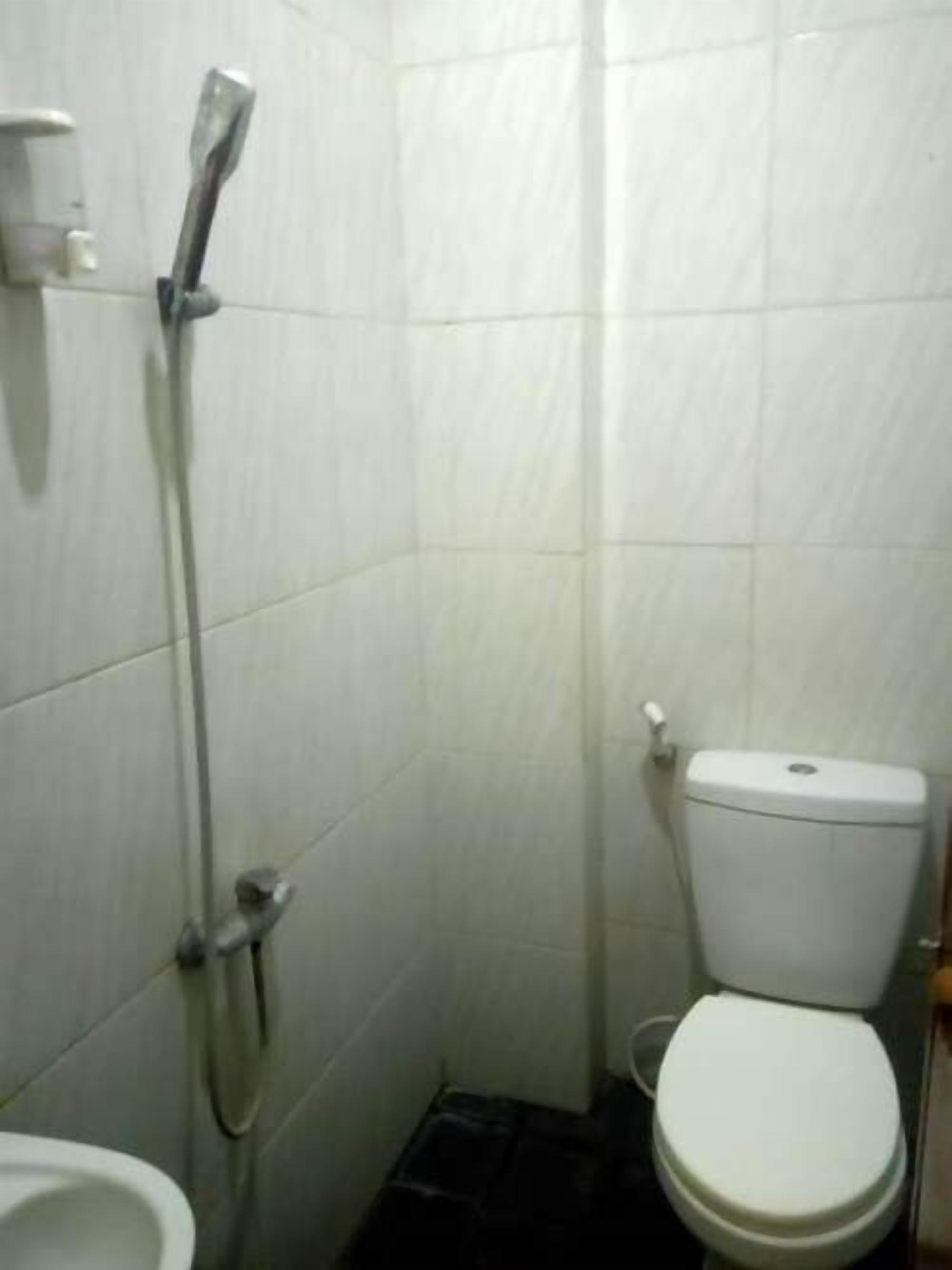 A small, tiled bathroom with a toilet, a shower, and a bidet.