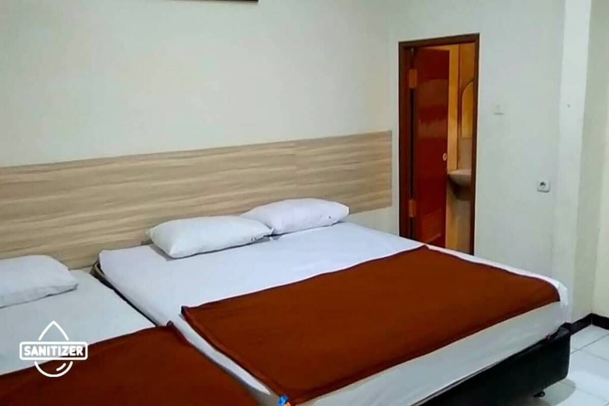 Ein Hotelzimmer mit zwei Betten, einem Holzkopfende und einer roten Tür.
