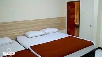 A hotel room with two beds, a wooden headboard, and a red door.