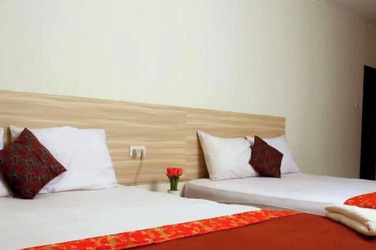 Ein Hotelzimmer mit zwei Betten, jeweils mit weißer Bettwäsche und einem roten dekorativen Rand.