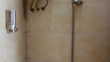 Een douche met een handdouche en een bedieningspaneel aan de muur.