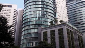 A tall, cylindrical glass building with a modern design, surrounded by other high-rise buildings. - Vortex Suite KLCC by Idaris (Kuala Lumpur)