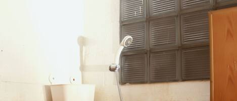 A shower area with orange tiles, a white sink, and a showerhead mounted on the wall.