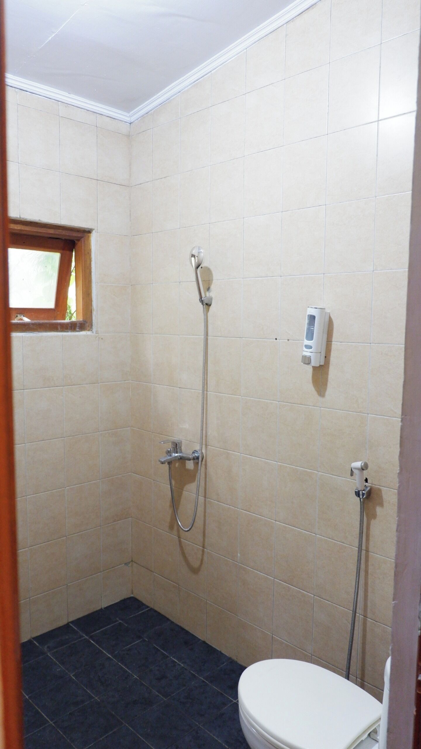 Ein kleines Badezimmer mit Toilette, Dusche und Fenster.