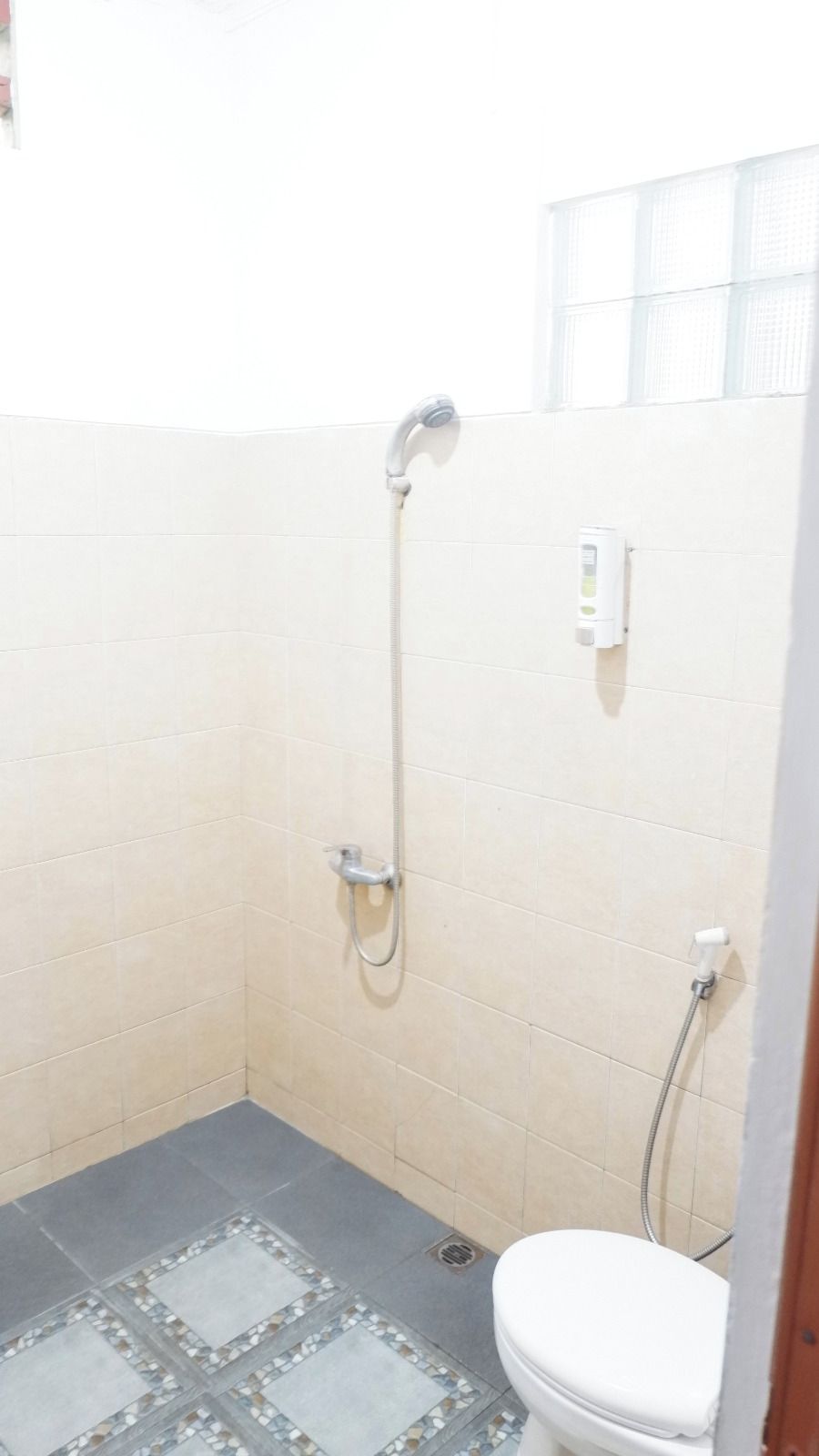 Un baño pequeño con ducha, inodoro y paredes de azulejos.