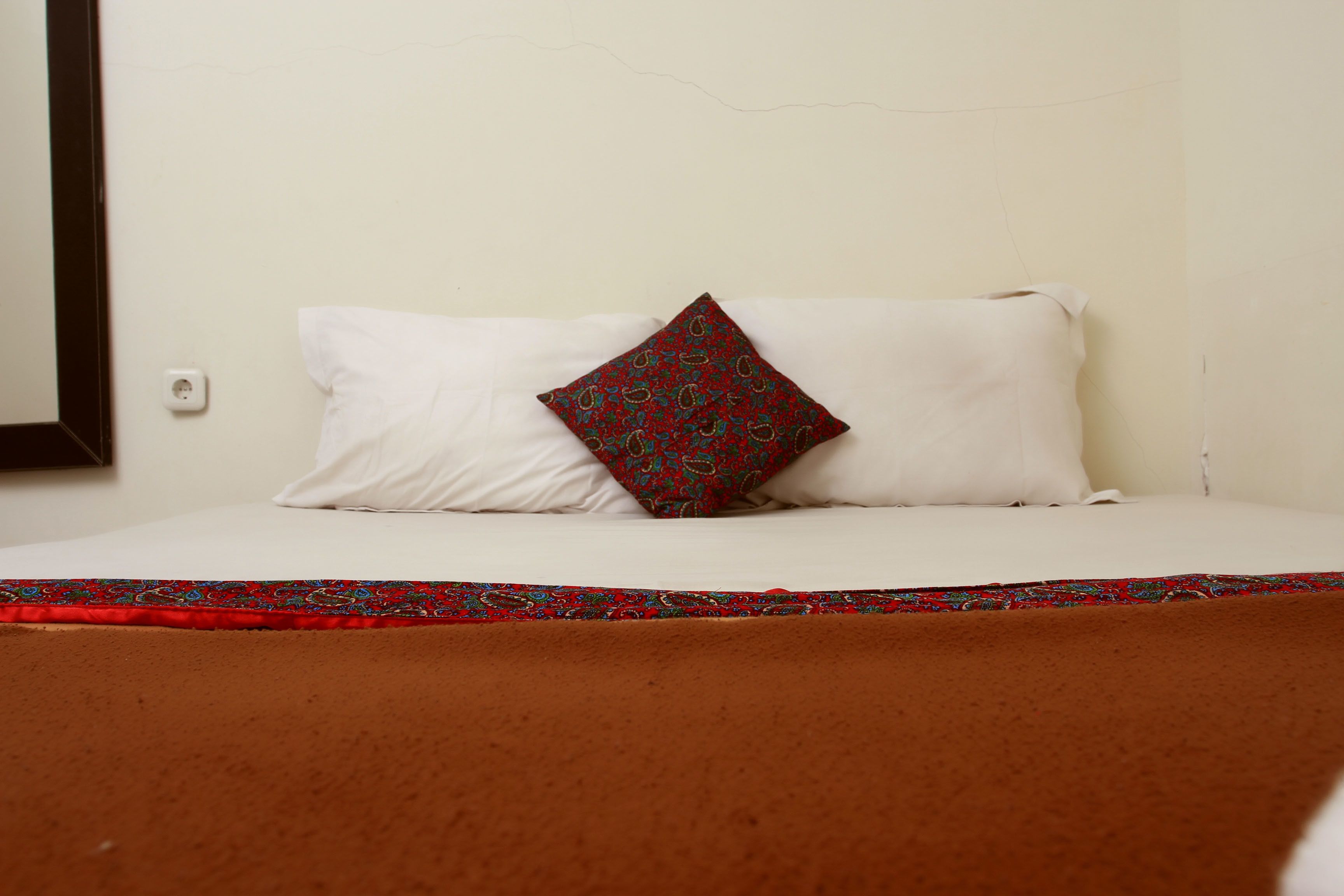 Una cama con ropa blanca y una almohada decorativa.