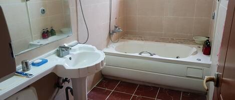 A bathroom with a pedestal sink, a bathtub, and a toilet.
