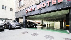 A Plus Motel with a covered parking area and several cars parked in front. - Plus Motel (Busan)