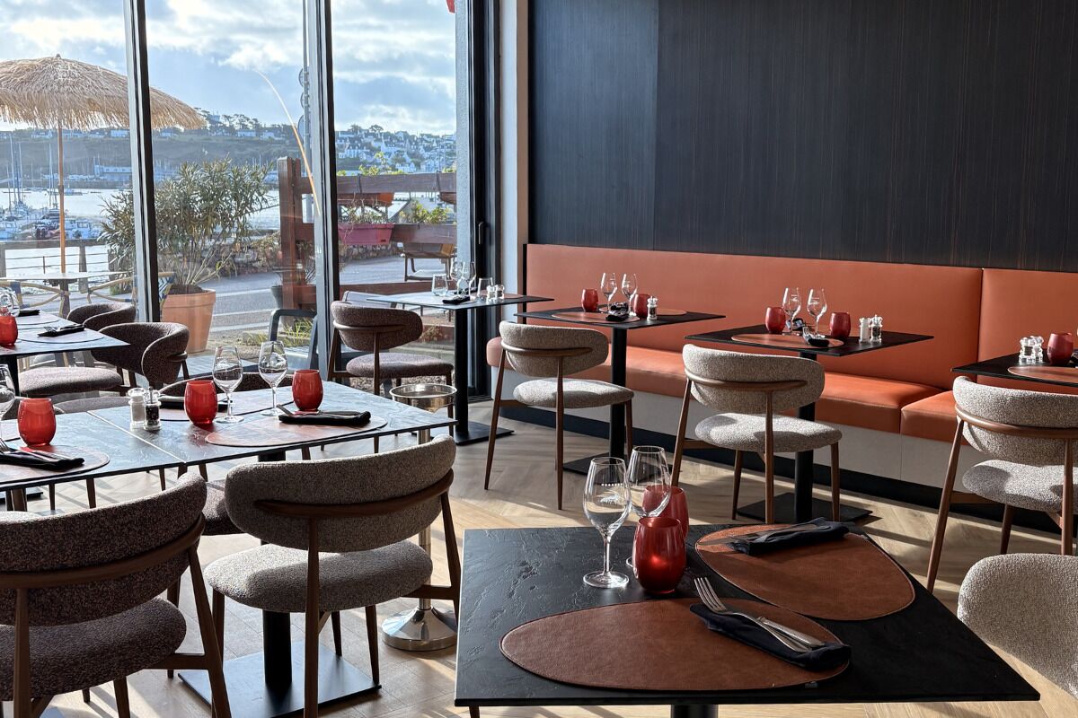 Ein Restaurant mit Tischen, Stühlen und Blick auf den Hafen, ausgestattet mit einem großen Fenster.