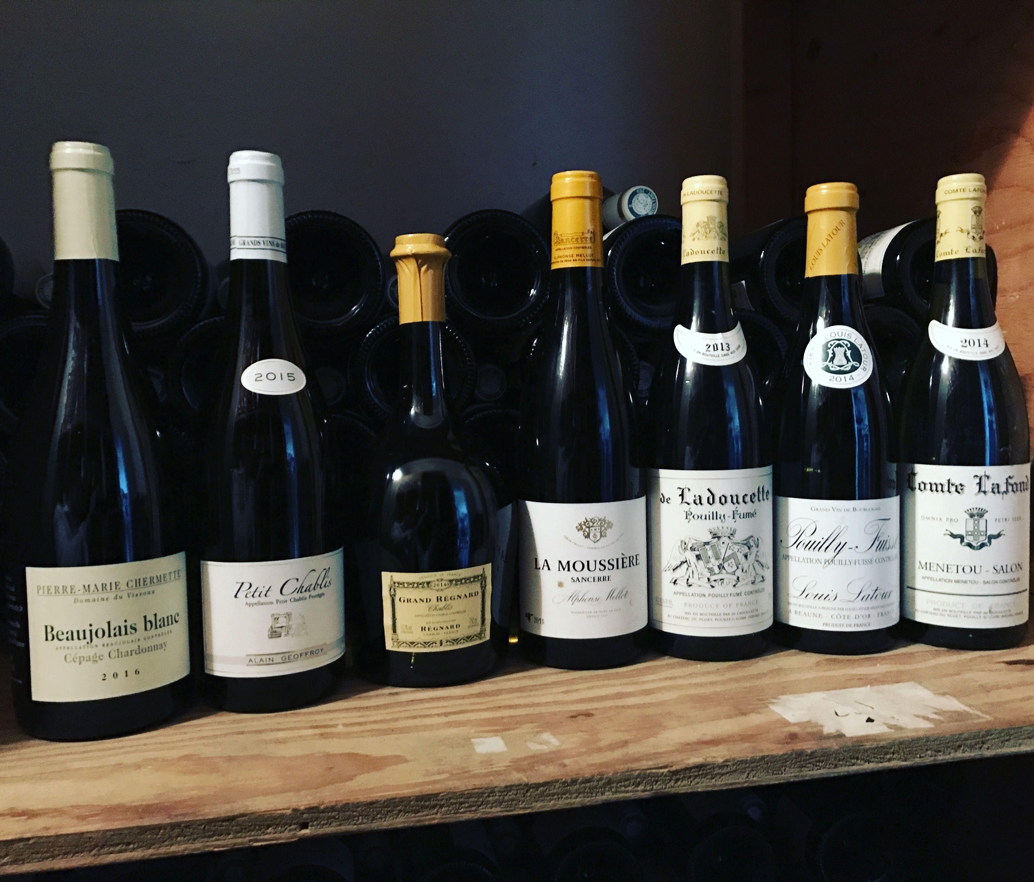 A collection of wine bottles on a wooden shelf.