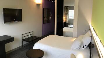 Une chambre d’hôtel avec un lit, un bureau, une chaise, une petite table et un téléviseur.