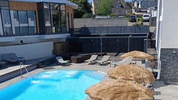 Una piscina al aire libre de temporada, sillones reclinables de piscina