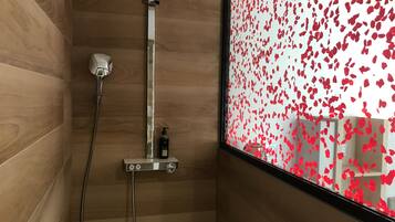 A shower with a handheld showerhead and a handheld shower attachment.