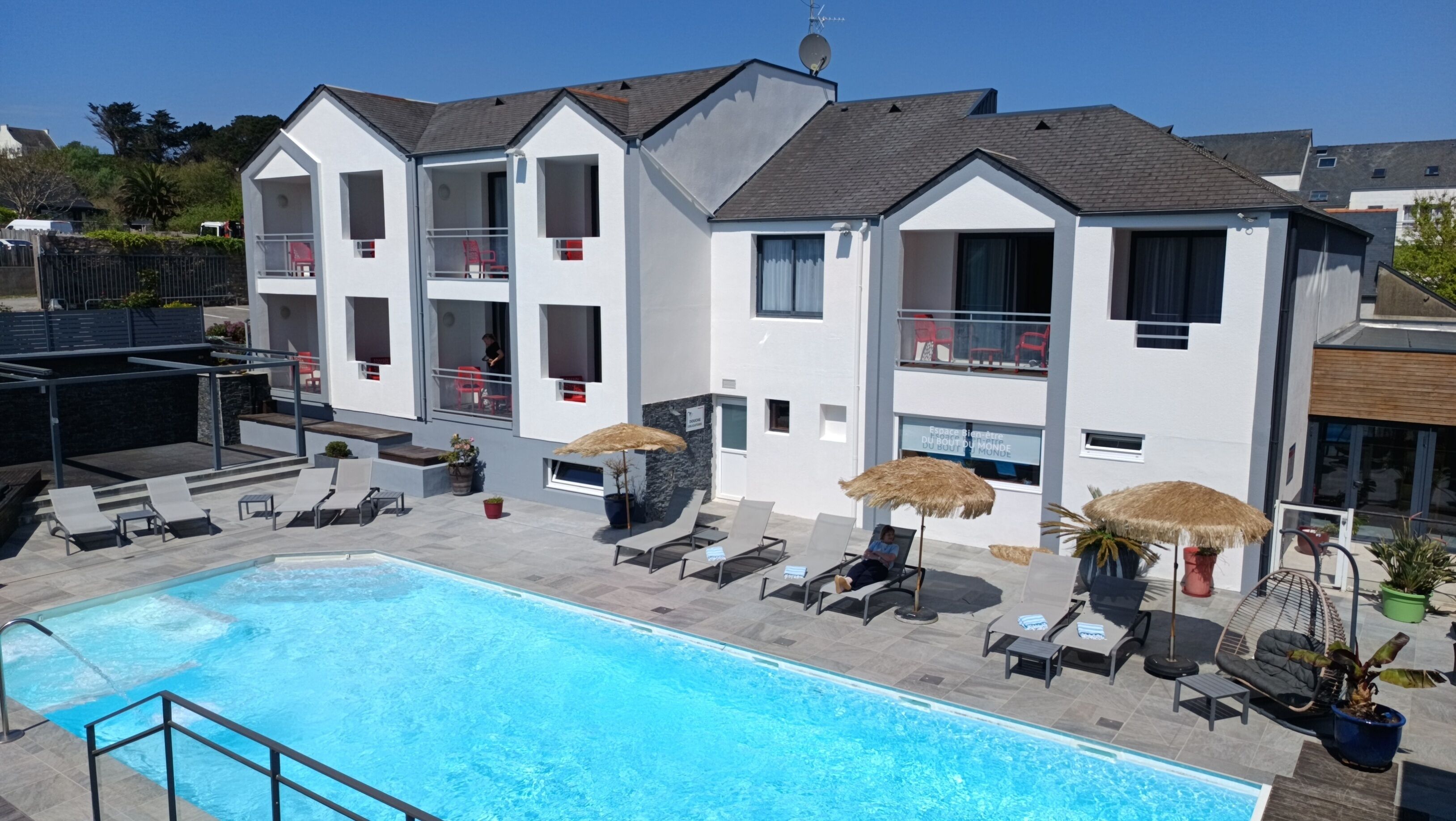 Un hôtel moderne doté d’une piscine, de chaises longues et de parasols.