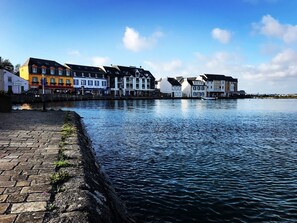 A waterfront hotel with a brick walkway, a row of colorful buildings, and a calm river. - Le Thalassa Hôtel & Spa (Camaret-sur-Mer)