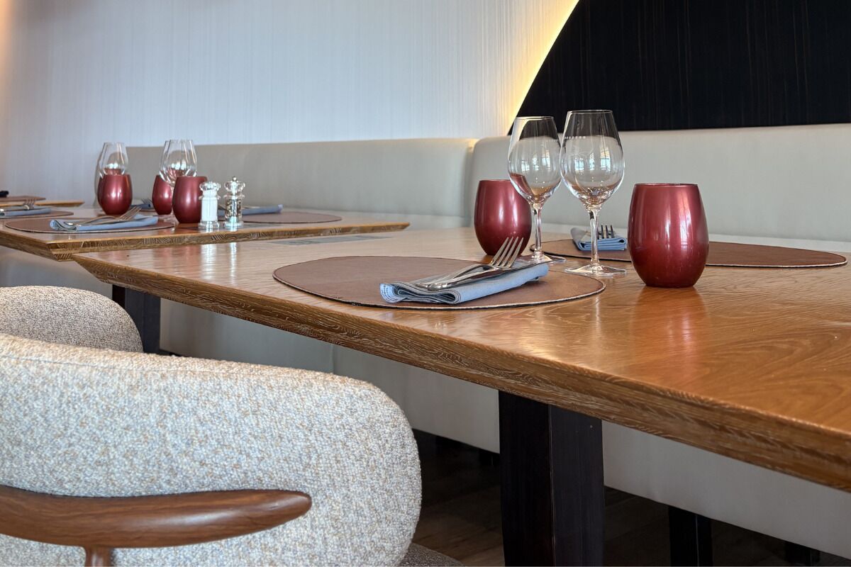 A dining area with wooden tables, red and clear glassware, and a modern interior design.