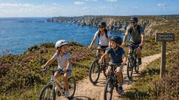 A family on a mountain bike trail with a sign reading 'Presqu'ile de Crozon'.