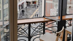En balkon med udsigt over en gade, en træstol og et mønstret gulv.