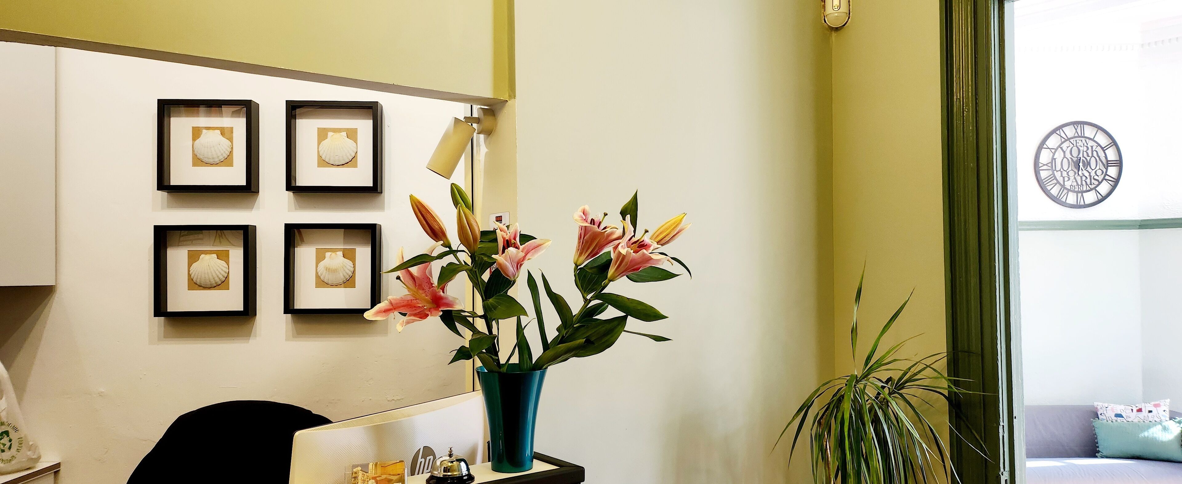 A reception area with framed artwork, a vase with flowers, and a clock on the wall.
