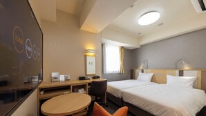 A hotel room with two beds, a desk, a chair, a TV, and a window with curtains.