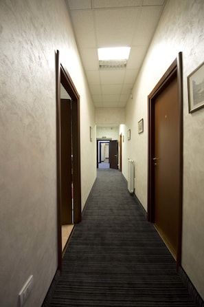 Ein Hotelgang mit Teppichböden, Türen auf beiden Seiten und gerahmten Bildern an den Wänden.