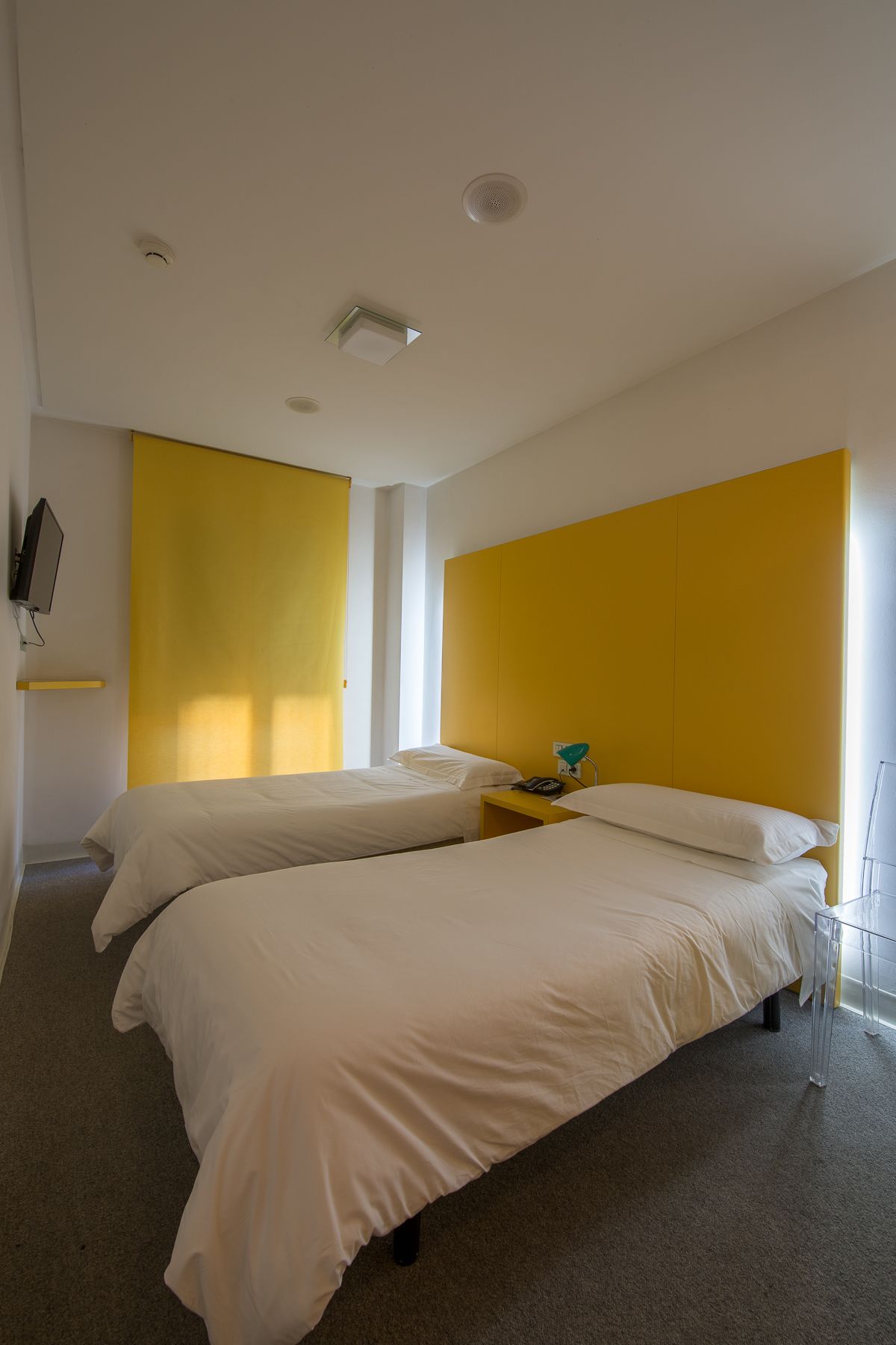 A modern hotel room with two beds, a desk, and a chair.