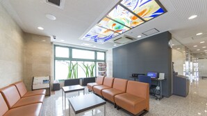 A modern waiting area with leather seating, a reception desk, and a large window providing natural light. - Sanco Inn Toyota (Toyota)