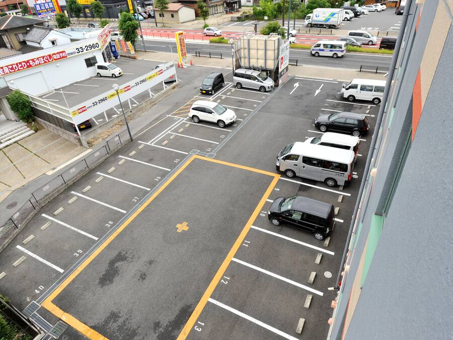 A parking lot with multiple rows of parking spaces, a large truck, and several cars parked.