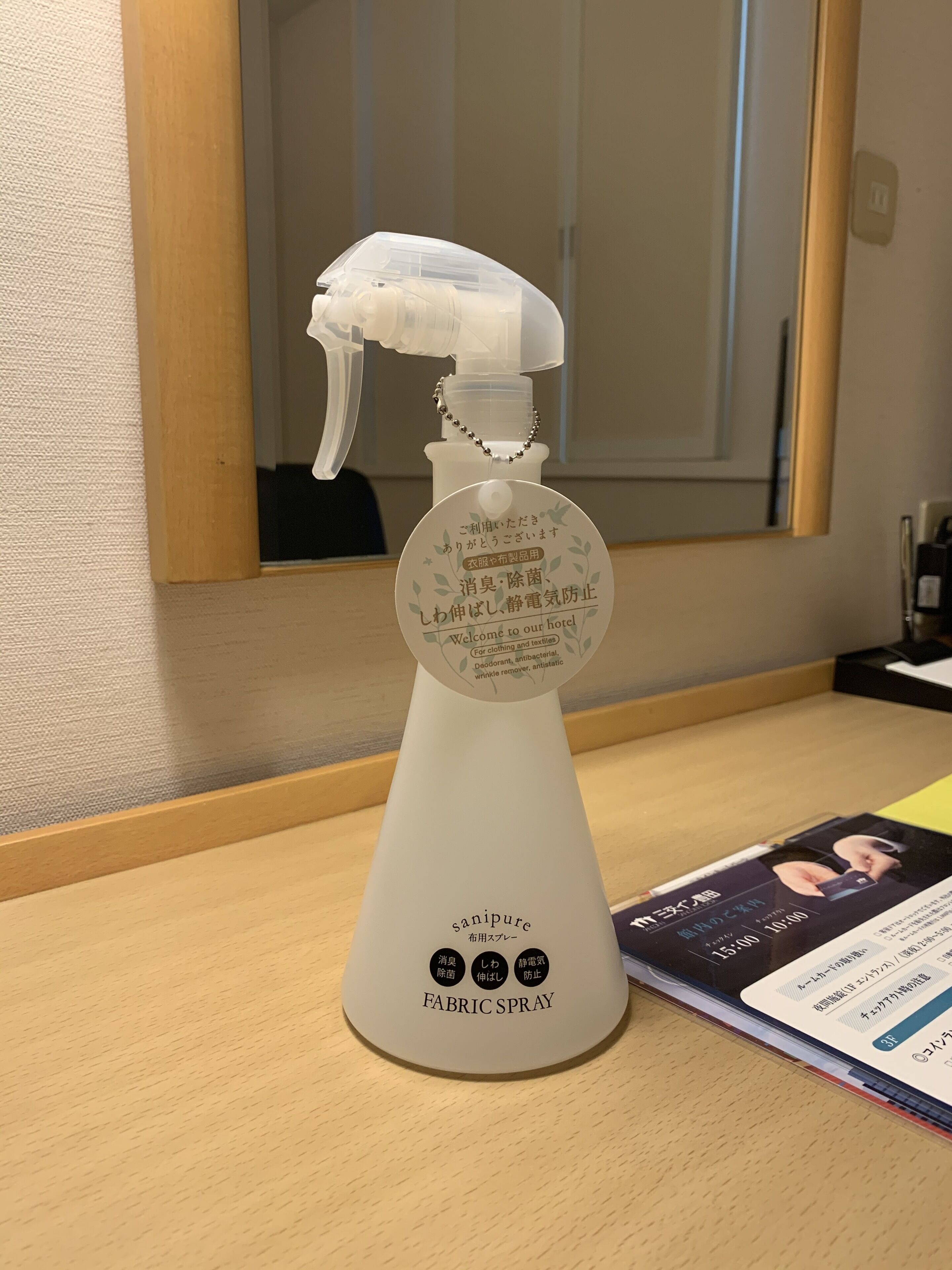 A fabric spray bottle on a wooden counter with a mirror above it.