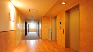 A long, well-lit corridor with tiled walls and floors, leading to an elevator. - Sanco Inn Toyota (Toyota)