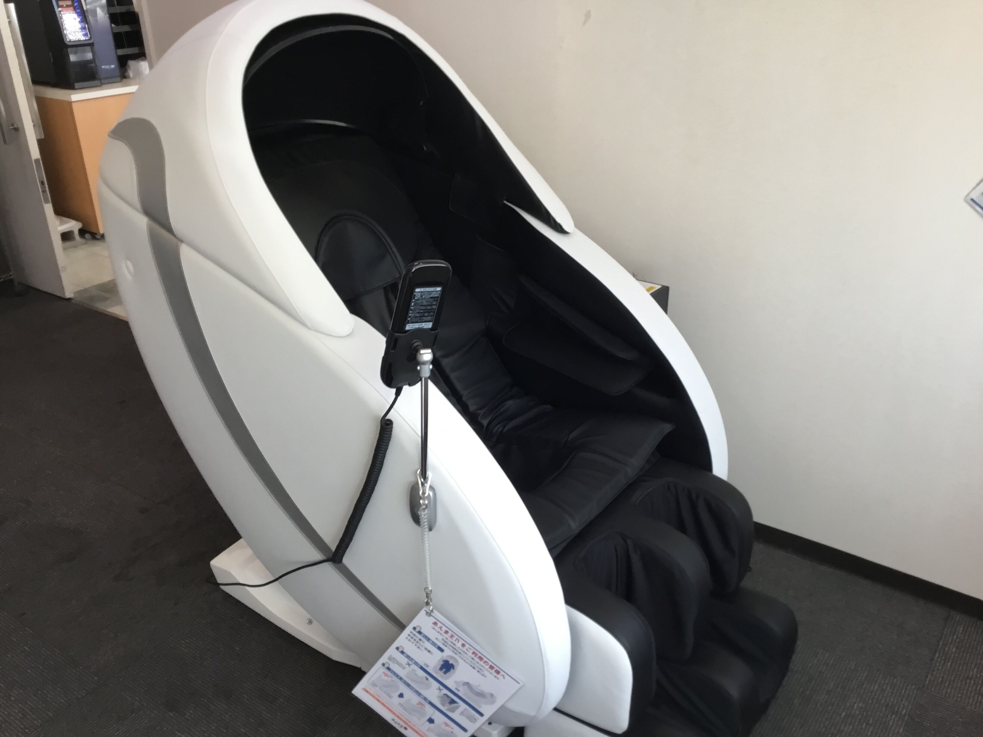 A massage chair with a control panel and a footrest.