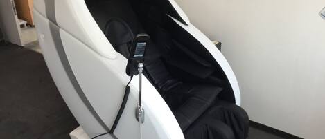 A massage chair with a control panel and a footrest.