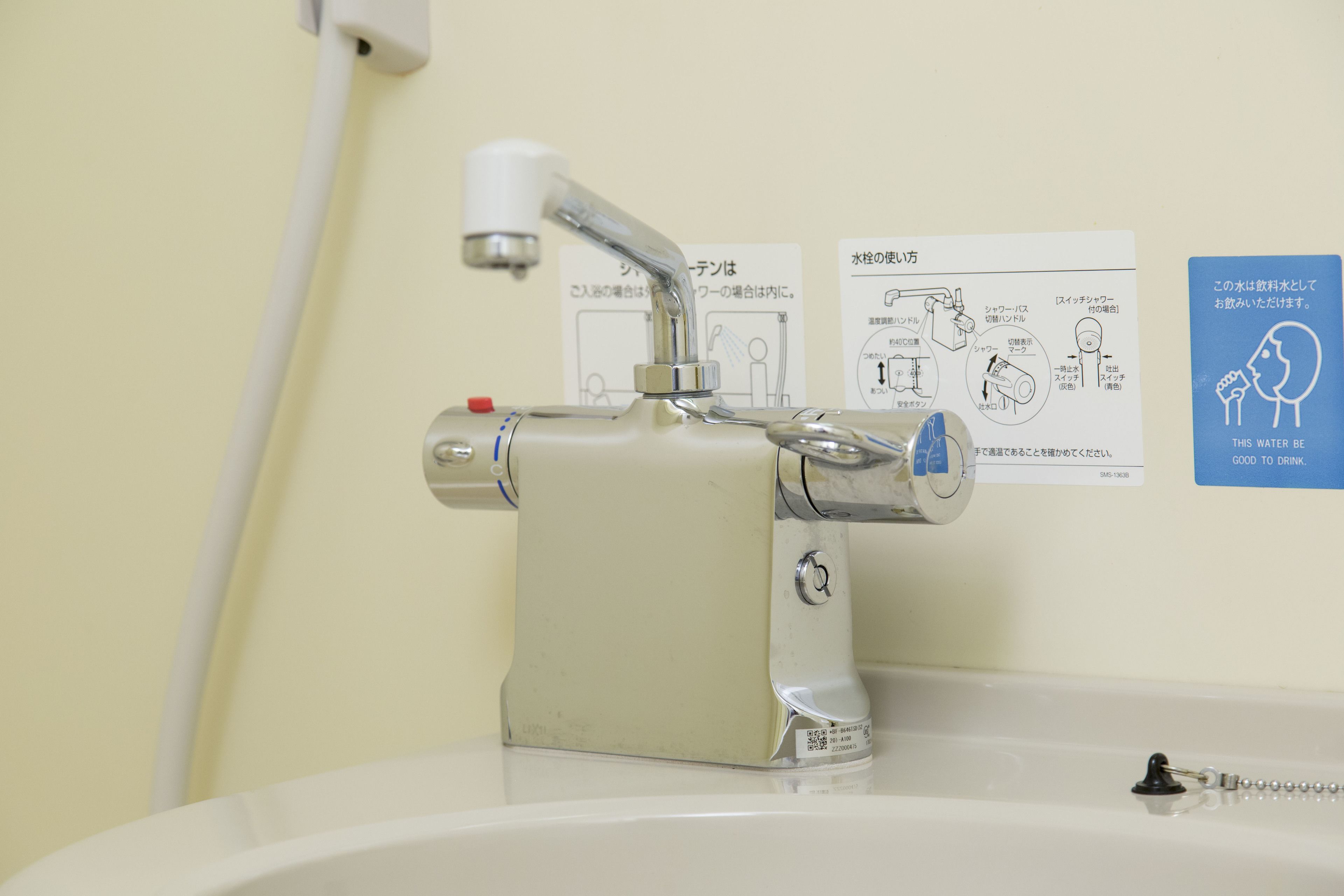 A bathroom sink with a faucet, a hand soap dispenser, and a paper with instructions.