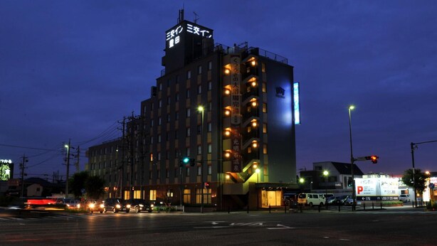 A multi-story hotel with illuminated signage and a prominent entrance. - Sanco Inn Toyota (Toyota)