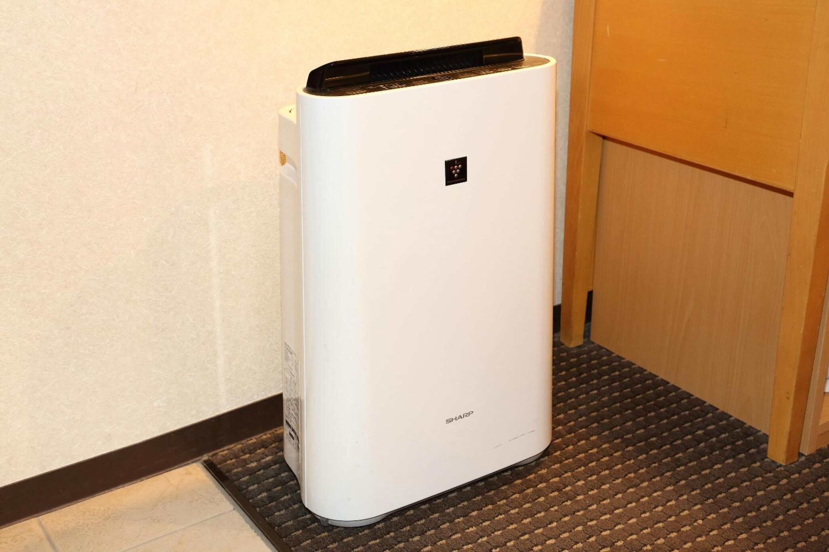 A white air conditioning unit with a control panel and a small logo on the top.