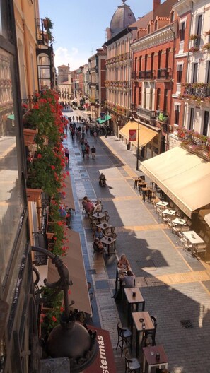 A bustling street with outdoor seating and a fountain, surrounded by historic buildings. - Hostal Albany Ancha (León)