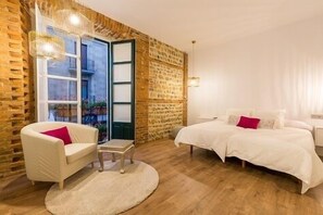 A bedroom with a bed, a chair, a small table, and a large window. - Hostal Albany Ancha (León)