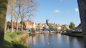 Een pittoresk stadje aan de rivier met historische gebouwen, een brug en een kerktoren.