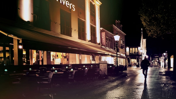 Een restaurant met rivieren als thema, met terras en een persoon die over straat loopt.