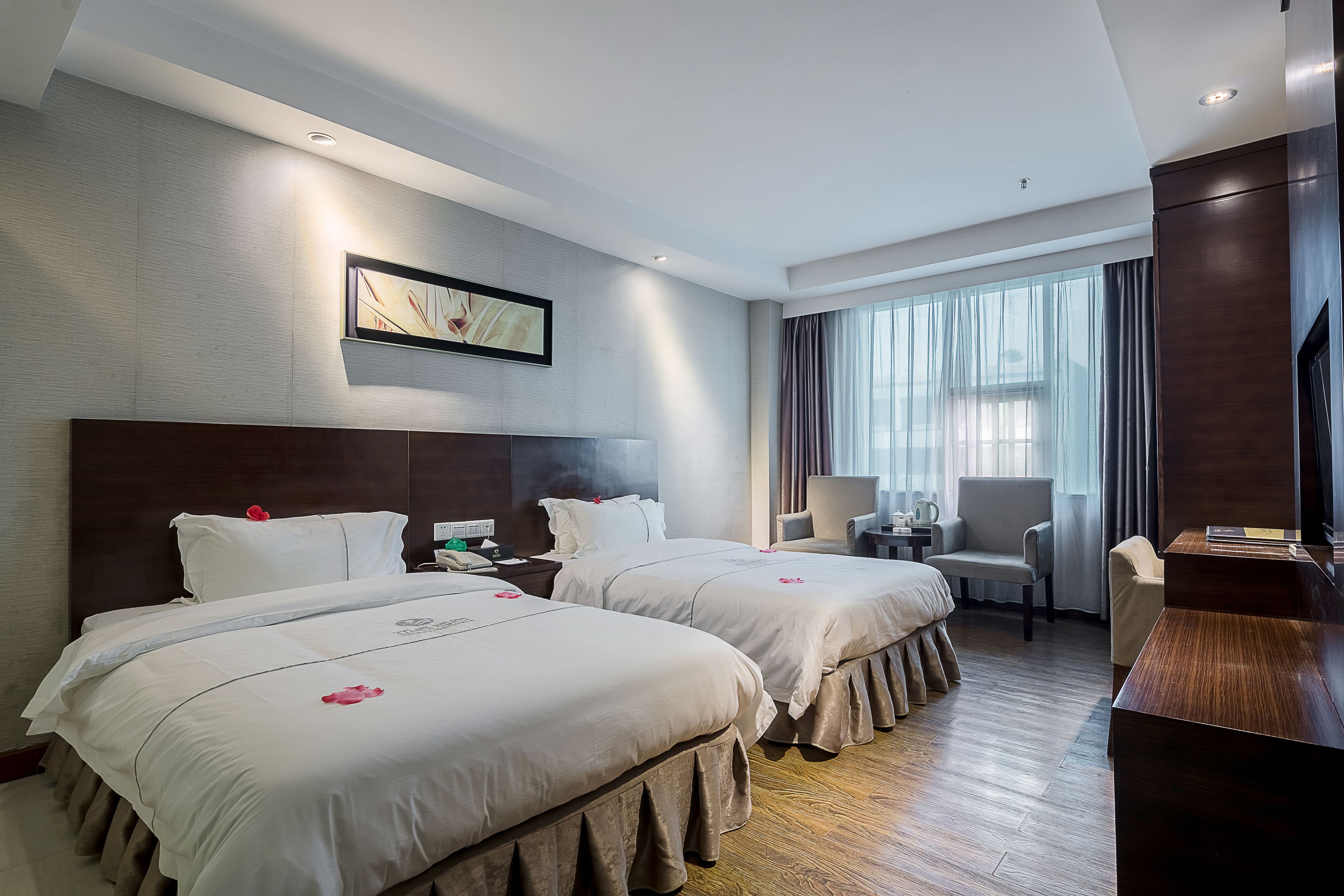 Une chambre d’hôtel avec deux lits, un bureau, une chaise et une grande fenêtre avec des rideaux.