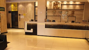 A hotel reception area with a modern design, featuring a reception desk, a digital screen, and a wall-mounted sign with the hotel name. - Huangpu Hotel (Guangzhou)